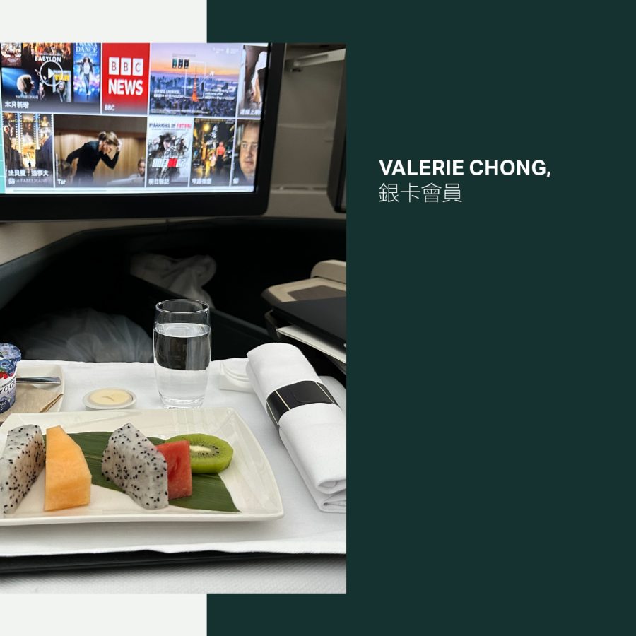 Fruit on a plate and a yoghurt pot with a screen above in the Business cabin on a Cathay Pacific flight.